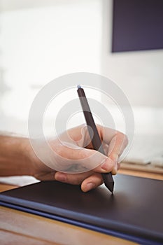 Cropped hand of man using graphics tablet