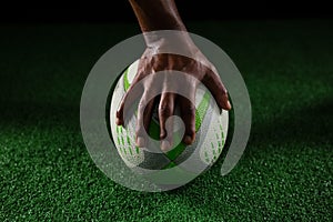 Cropped hand of sportsperson on rugby ball