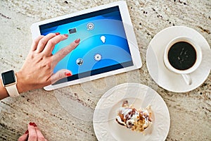 Cropped hand of woman using tablet computer while preparing  breakfast