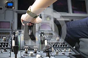 Cropped hands of pilot flying a commercial airplane, cockpit view close up of hands. Captain hand accelerating on the throttle in