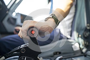 Cropped hands of pilot flying a commercial airplane, cockpit view close up of hands. Captain hand accelerating on the throttle in