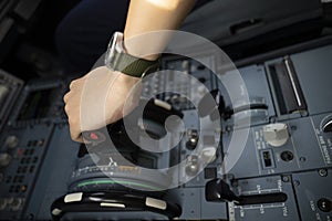 Cropped hands of pilot flying a commercial airplane, cockpit view close up of hands. Captain hand accelerating on the throttle in