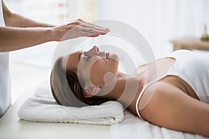 Cropped hands of therapist performing reiki on woman