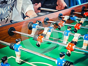 Cropped image of active people playing foosball. table soccer plaers. Friends play together table football