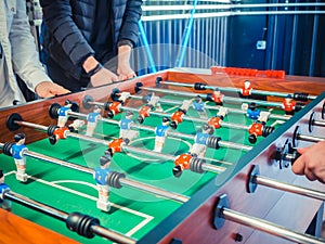 Cropped image of active people playing foosball. table soccer plaers. Friends play together table football