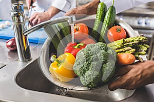 cropped image of african american chef washing vegetables