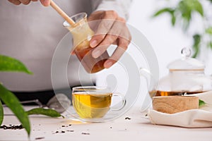 Cropped image of arista pouring honey into cup of tea