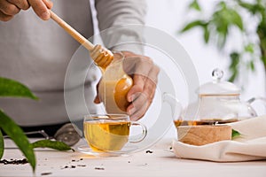 Cropped image of arista pouring honey into cup of tea