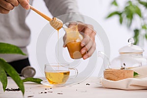 Cropped image of arista pouring honey into cup of tea