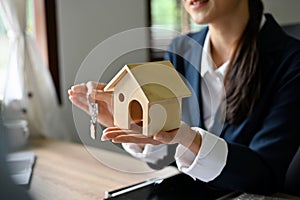 Cropped image, Asian female real estate agent holding a house model and house key