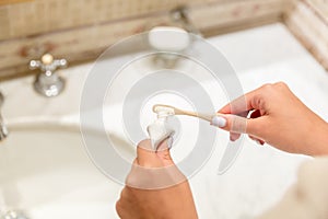 Cropped image of attractive woman hand applying toothpaste on toothbrush in bathroom. Beauty healty wellness morning concept