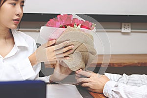 Cropped image of attractive young Asian woman accepting a bouquet of red roses from boyfriend in office on valentine`s day. Love