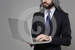Cropped image of bearded arabian muslim businessman in keffiyeh kafiya ring igal agal black suit  on gray photo