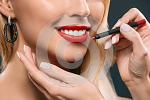 cropped image of beautiful blonde hair girl with visagiste applying lipstick with brush,