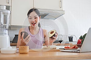 Cropped image of a beautiful and fit Asian woman in gym clothes cutting an avocado and preparing her healthy breakfast