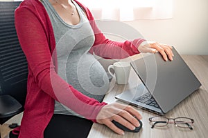 Cropped image of beautiful pregnant business woman closing a laptop and holding one hand on mouse while finishing working from hom