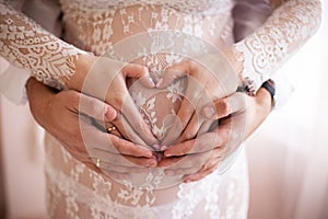 Cropped image of beautiful pregnant woman and her handsome husband hugging the tummy