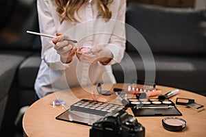cropped image of beauty blogger holding makeup brush and eyeshadow