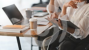 Cropped image of business developer team discussing/planning/meeting by using a computer tablet .