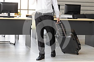 Cropped image of business man holding passport and luggage in workplace of office. Summer vacations concept
