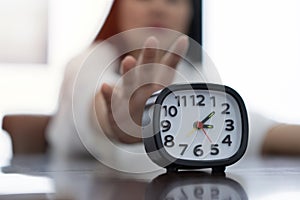 Cropped image of business woman with alarm clock working under deadline in office