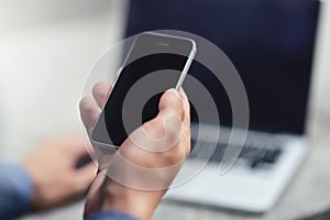 Cropped image of businessman with laptop at street sending text messages to coworker.