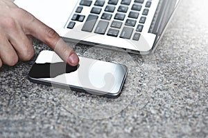 Cropped image of businessman with laptop at street sending text messages to coworker