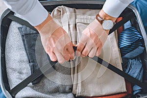 cropped image of businessman with wristwatch packing luggage