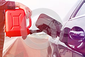 Cropped image of businesswoman with canister fueling car against sky