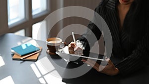 Cropped image of businesswoman holding using computer tablet with stylus pen.