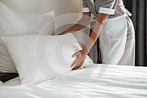 Cropped image of a chambermaid making bed in hotel room