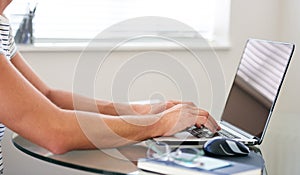 Cropped image of composed man`s hands typing on a laptop