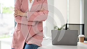 Cropped image of a confident businesswoman sits on a table with her arms crossed