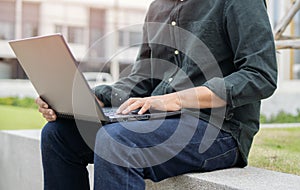 Cropped image of corporate man working outside office on remote, sitting with laptop