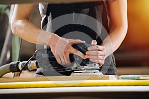 Cropped image of a craftsman grinding a wooden plank. No head, close up