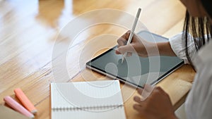 Cropped image of creative woman`s hand holding/using a stylus pen to drawing on white blank screen computer tablet.