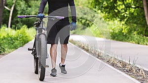 Cropped image of cycler holding bike in public park