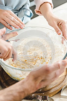 cropped image of family hands mixing dough together