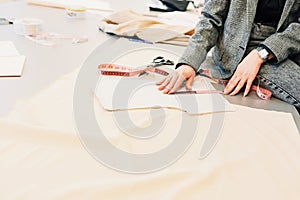 Cropped image of a fashion female designer looking at new fabric for an online store. Young woman business owner sitting on the