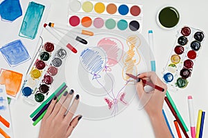 cropped image of female artist drawing air balloons at white table with colorful