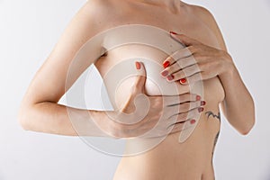 Cropped image of female body, breast isolated over grey studio background. Plastic surgery, mammoplasty, female health.