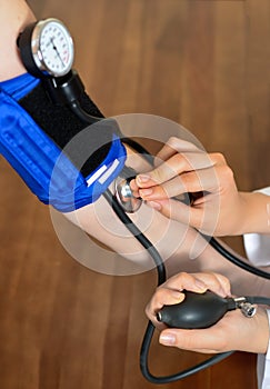 Cropped image of Female doctor checking blood pressure of patient at table