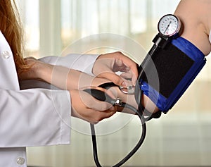 Cropped image of Female doctor checking blood pressure of patient at table