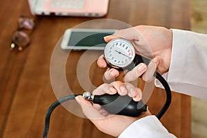 Cropped image of Female doctor checking blood pressure of patient at table