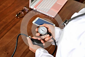 Cropped image of Female doctor checking blood pressure of patient at table