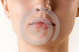 Cropped image of female face, lips and nose over white background. Lip augmentation and anti-wrinkle fillers