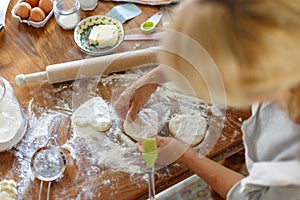 Cropped image of a female hands holding dough in heart shape top view. Baking ingredients on the wooden table