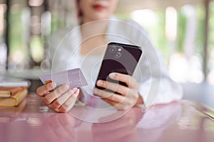 A cropped image of a female sits at a table in a cafeteria using a mobile banking app