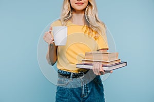 cropped image of girl holding books and cup of coffee