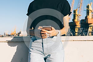 Cropped image of a girl holding a phone in the city in the summer